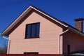 Facade of a house with a pink wall and a brown window against the blue sky Royalty Free Stock Photo