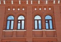 Facade of a restored city building made of red brick with arched windows. Element of architecture