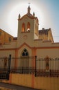 Facade of small church and belfry, behind iron fence, with sunshine behind at sunset in SÃ£o Manuel. Royalty Free Stock Photo