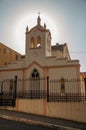 Facade of small church and belfry, behind iron fence, with sunshine behind at sunset in SÃÂ£o Manuel. Royalty Free Stock Photo