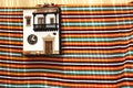 Facade of a traditional miniature house hanging on the wall with a colorful cloth underneath