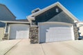 Facade of two car garage with gable roof dormer and gray wall against blue sky