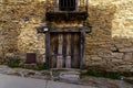 Facade of a very old house with a wooden door and a balcony with iron bars. La Hiruela Madrid