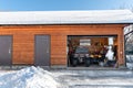 Facade view open door ATV home garage with quad bikes offroad vehicle parked sunny snowy cold winter day. ATV adventure Royalty Free Stock Photo