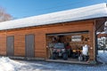 Facade view open door ATV home garage with quad bikes offroad vehicle parked sunny snowy cold winter day. ATV adventure Royalty Free Stock Photo