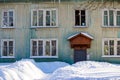 Facade of a wooden apartment building and heaps of snow on a winter da