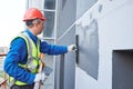 Facade worker plastering external wall of building