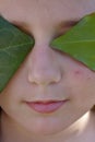 The face of an angel covered by green leaves