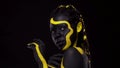 Face art. Dancing woman with black and yellow body paint. Young african girl with colorful bodypaint. An amazing afro