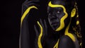 Face art. Dancing woman with black and yellow body paint. Young african girl with colorful bodypaint. An amazing afro