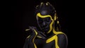 Face art. Dancing woman with black and yellow body paint. Young african girl with colorful bodypaint. An amazing afro