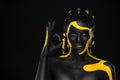 Face art. Girl showing ok sign with fingers. Woman with black and yellow body paint. Young african girl with colorful