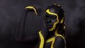 Face art. Dancing woman with black and yellow body paint. Young african girl with colorful bodypaint. An amazing afro