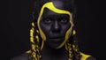 Face art. Woman with black and yellow body paint. Young african girl with colorful bodypaint. An amazing afro american