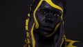 Face art. Woman with black and yellow body paint. Young african girl with colorful bodypaint. An amazing afro american