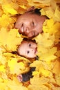 Face of baby boy and his mother under maple leaves Royalty Free Stock Photo