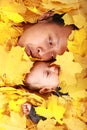 Face of baby boy and his mother under maple leaves Royalty Free Stock Photo