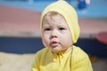 Face baby girl boy portrait close-up. The child in a yellow knit hat outdoors