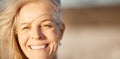 Face of beautiful mature woman on the beach. Smiling senior woman enjoying a beach holiday. Closeup on face of happy