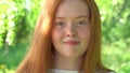 The face of a beautiful red-haired girl in backlight. Portrait a smiling young woman with red hair and freckles against Royalty Free Stock Photo