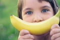 Face of a beautiful young Caucasian girl with banana smile on nature background.