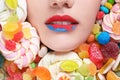 Face of beautiful young woman with creative makeup surrounded by different sweets, closeup