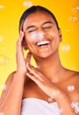 Face, beauty and bubbles with a woman laughing on a yellow background in studio for freedom, energy or wellness