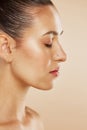 Face, beauty and skincare with a model woman profile posing in studio on a beige background for wellness. Cosmetics