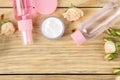 Face and body cosmetics in pink bottles with fresh roses on a natural wooden background. creams and lotion. spa. top view. space f Royalty Free Stock Photo