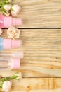 Face and body cosmetics in pink bottles with fresh roses on a natural wooden background. creams and lotion. spa. top view. space f Royalty Free Stock Photo