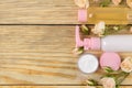 Face and body cosmetics in pink bottles with fresh roses on a natural wooden background. creams and lotion. spa. top view. space f Royalty Free Stock Photo