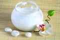 Face and body cream, pebbles and orchid on bamboo Royalty Free Stock Photo