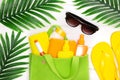 Face and body sunscreen products and towels in eco bag with sunglasses and flip flop sandals framed by tropical palm leaves Royalty Free Stock Photo