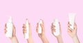 Face and body wash. Women holding bottles and tube of cosmetic products on pink background, closeup. Collage design