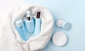 Face care products tonic or lotion, serum, cream, micellar water, cotton pads covered in towel on blue, powder background. Royalty Free Stock Photo