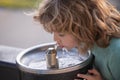 Face close up portrait of child drinking water from tap or water outdoor in park. Close up portrait of kid drinking Royalty Free Stock Photo