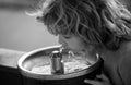 Face close up portrait of child drinking water from tap or water outdoor in park. Close up portrait of kid drinking Royalty Free Stock Photo