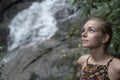 Face closeup of pretty blonde woman looking up over blurred waterfall