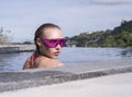 Face closeup of young woman wearing purple sunglasses looking at camera in infinity rooftop swimming pool on a sunny day over Royalty Free Stock Photo