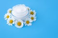 Face cream in a glass jar on a blue background, skin care concept. Chamomile flowers and moisturizer. Herbal natural cosmetic Royalty Free Stock Photo