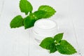 Face cream in glass jar with green leaves of urtica