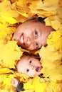 Face of baby boy and his mother under maple leaves Royalty Free Stock Photo