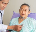 Face of elderly patient man unhappy, suffer, sadness from sick looking forward and doctor using stethoscope on heart. Doctor or Royalty Free Stock Photo