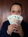 face with emotion expression of a young man with argentinean banknotes