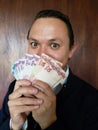 face with emotion expression of a young man and holding brazilian banknotes