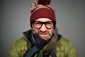 Face of european angry and furious male in warm clothes and glasses on a gray background.