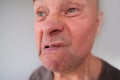 Face of a European old man close-up, wrinkles on the aging skin, bares his teeth, makes grimaces, opening his mouth, the concept Royalty Free Stock Photo