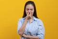 Face expression of human. Asian female smelling disgusted odor and pinching his nose in studio shoot yellow background