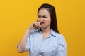 Face expression of human. Asian female smelling disgusted odor and pinching his nose in studio shoot yellow background