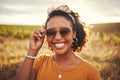 Face, fashion and nature with a black woman outdoor on a field with green grass in sunglasses and a smile. Happy Royalty Free Stock Photo